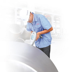 Portable alloy analyzer in use on a large fitting.