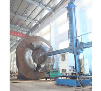 Column-and-boom automatic welding machine beside a large formed head.
